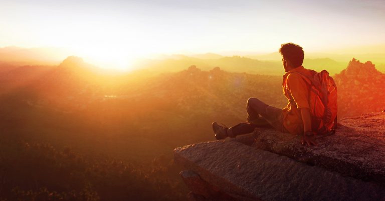 A young chap sitting in high mountains.