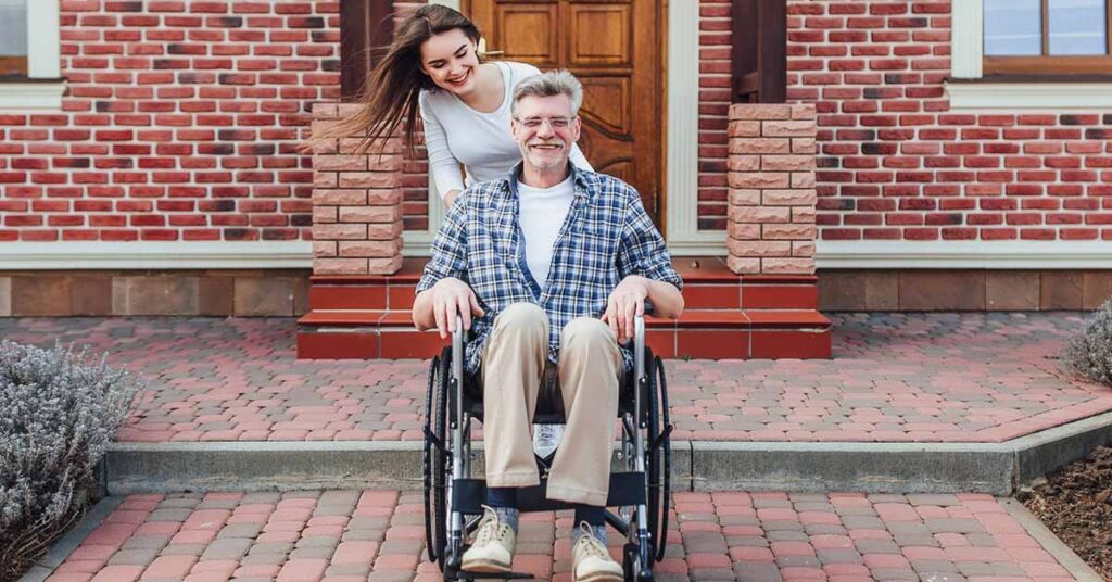 Young beautiful daughter with elderly father on wheelchair at home