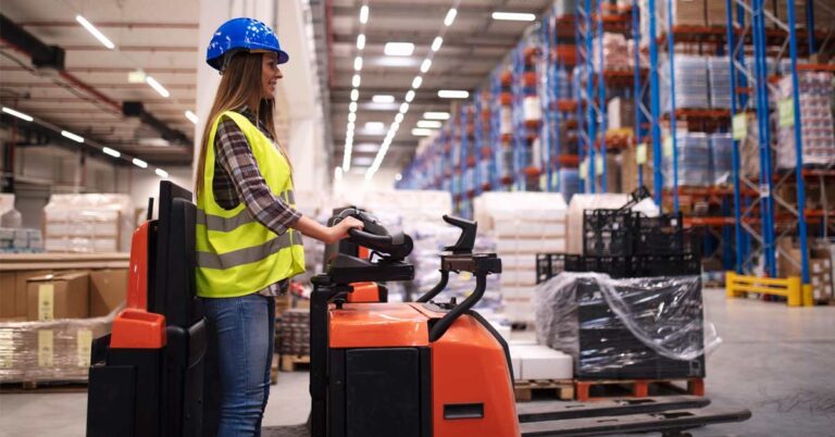 A Woman warehouse worker operating forklift machine in large distribution warehouse center