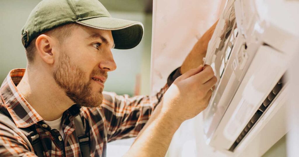 A white male technician repairing indoor AC