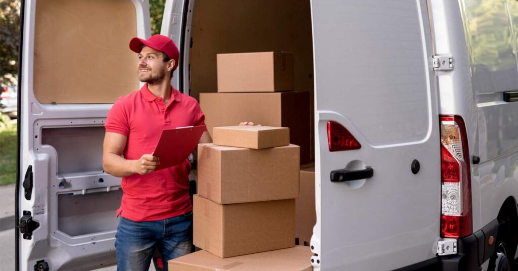 A male moving agent in red t-shirt loading boxes in a van.