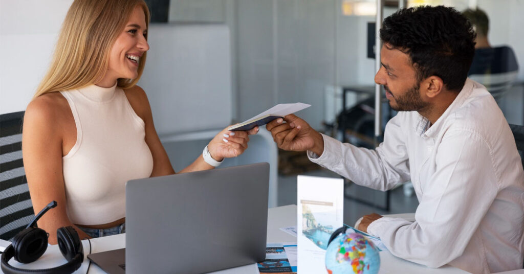 An attractive female travel agent handing over papers to a male customer