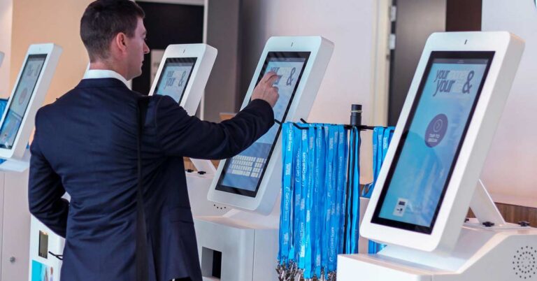 A male event attendee in a black suit using a kiosk to register for an event