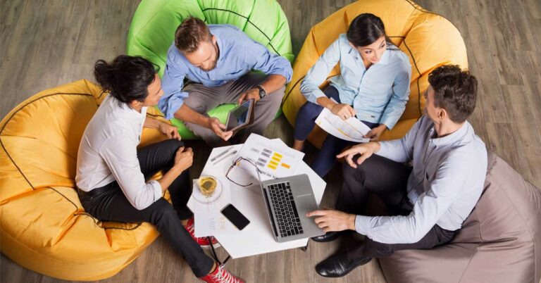 A group of four employees communicating while sitting on couches