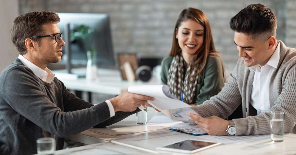 A male financial advisor advising a husband-wife couple