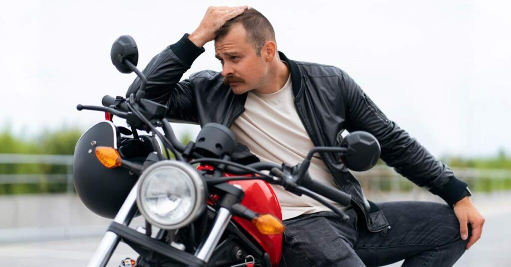 A man with sad expression sitting on a mototcycle