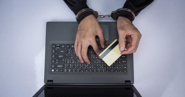 A laptop with handcuffed hands of a man holding a credit card - depicting digital arrest concept