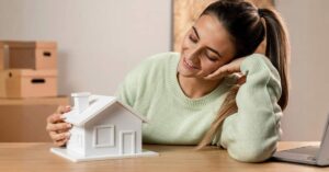 A beautiful Indian girl sitting and holding a miniature model of house hut