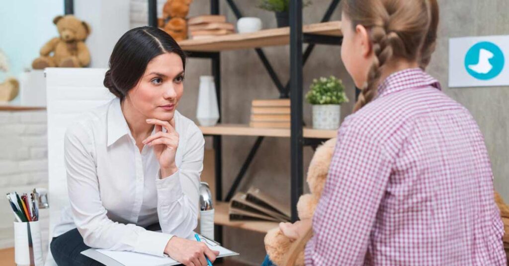 A white female counselor listening to a girl child