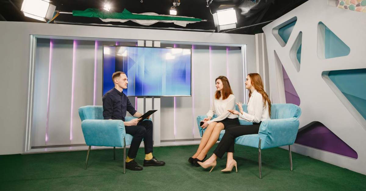 A male TV Presenter interviewing two female speakers