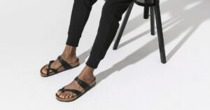 Picture showing feet of a black man wearing a black leather sandle.