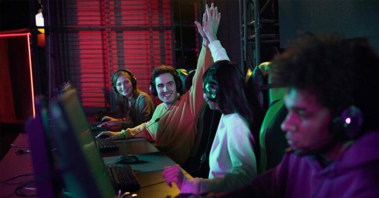 A group of four happy young people sitting in a multimedia room setting.