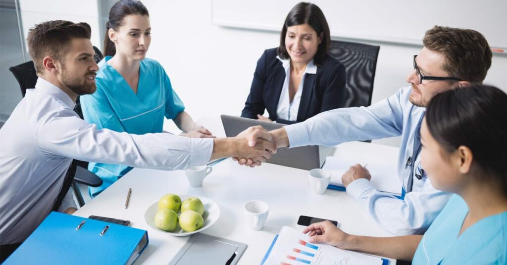 A group of company employees and doctors sitting together in a corporate office setting.
