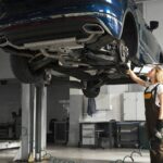 A woman worker operating a 2 post car lift, in a garage setting