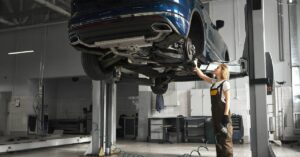 A woman worker operating a 2 post car lift, in a garage setting