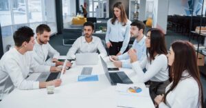 A team sitting in an office setting with individual laptop devices - depicting a knowledge management concept