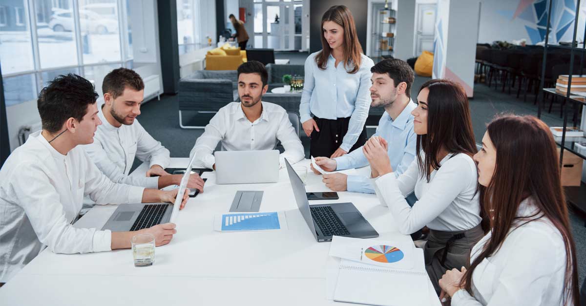 A team sitting in an office setting with individual laptop devices - depicting a knowledge management concept