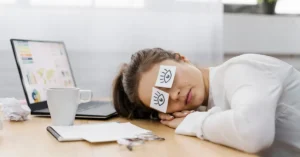 Female entrepreneur asleep on her laptop in an office, showing fatigue and stress from long work hours and sleep deprivation