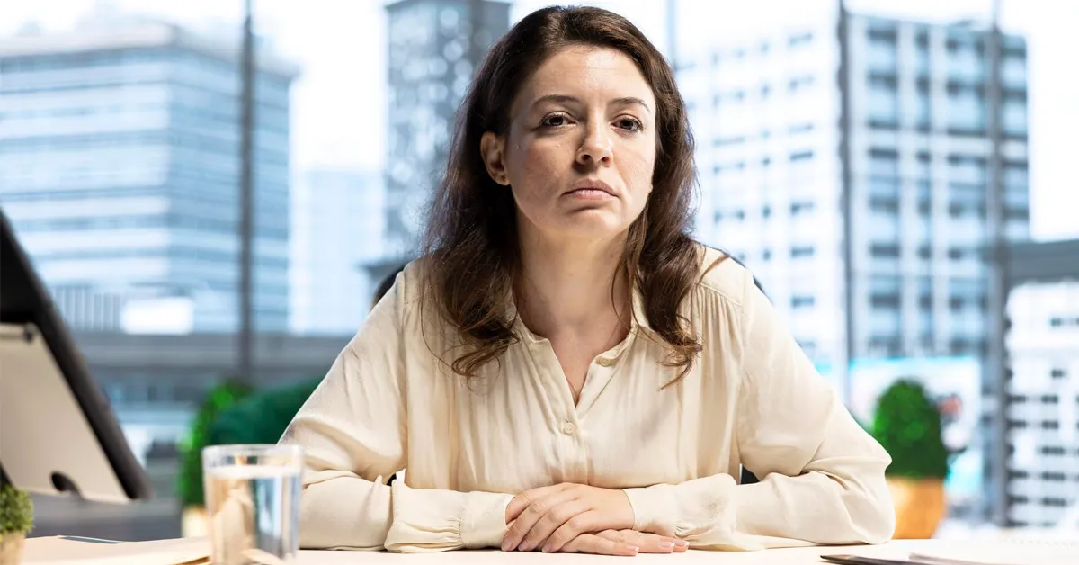 A sad female entrepreneur sitting with her head down at her desk, looking stressed and overwhelmed, symbolizing startup burnout and mental health challenges faced by founders.