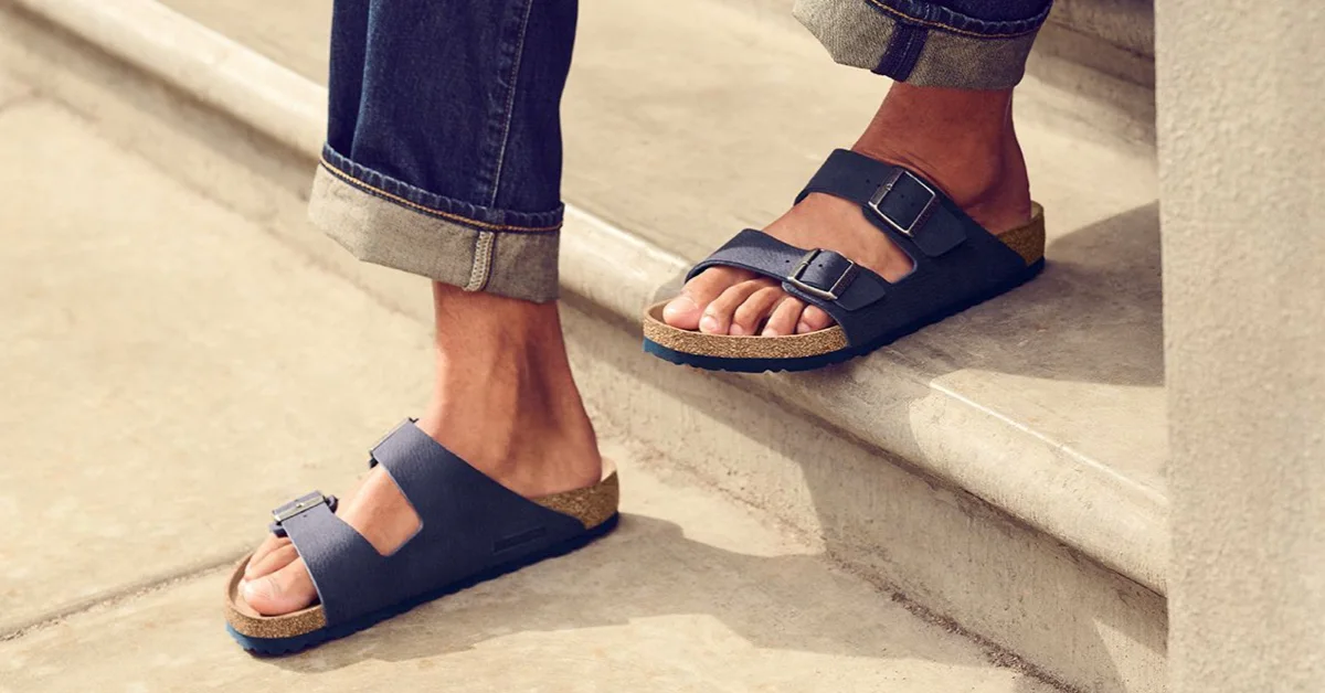 A guy wearing blue colored leather sandals