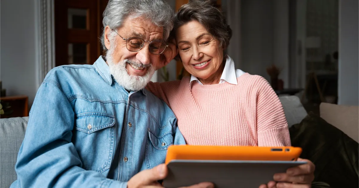 An old-age couple exploring a pension plan scheme on a tablet device with happy faces.