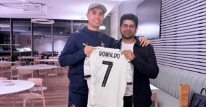 Cristiano Ronaldo, left, and Perplexity CEO Aravind Srinivas, right, hold a signed CR7 football jersey reading "To Arvind, Best Regards" during their AI investment partnership announcement.