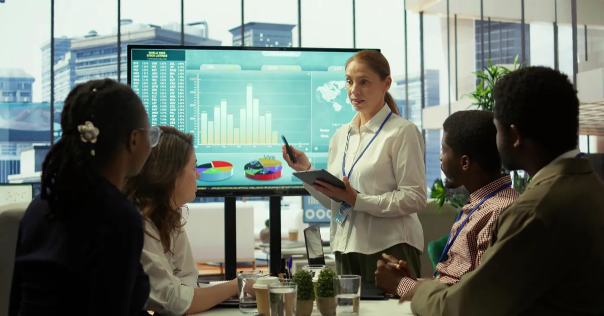 Manager presenting performance dashboard to team in office meeting illustrating transactional leadership and performance-based management.