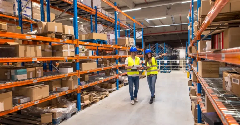 Two warehouse workers walking through a distribution center discussing logistics and storage organization.
