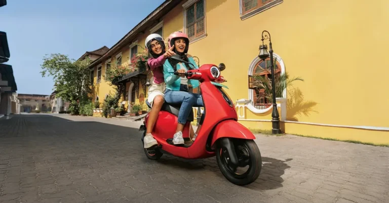 Electric two-wheeler scooter riding through busy urban traffic in India, highlighting the rise of e-scooters for city commuting.