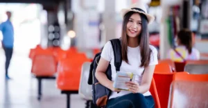 International student at airport departure terminal with luggage preparing to board a flight abroad