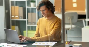 A professional focused on a laptop at an office workspace, representing career skill development