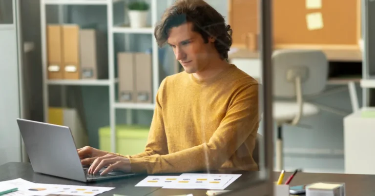 A professional focused on a laptop at an office workspace, representing career skill development