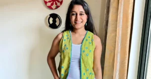 IndiKhoj founder Anoushka Upadhyaya standing against a plain wall, smiling at the camera